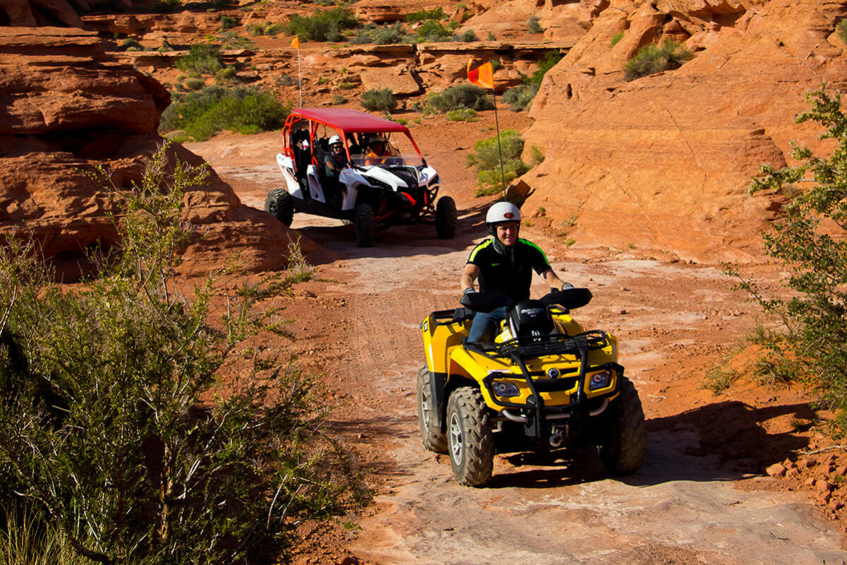 ATV leading UTV on tour through red rocks.