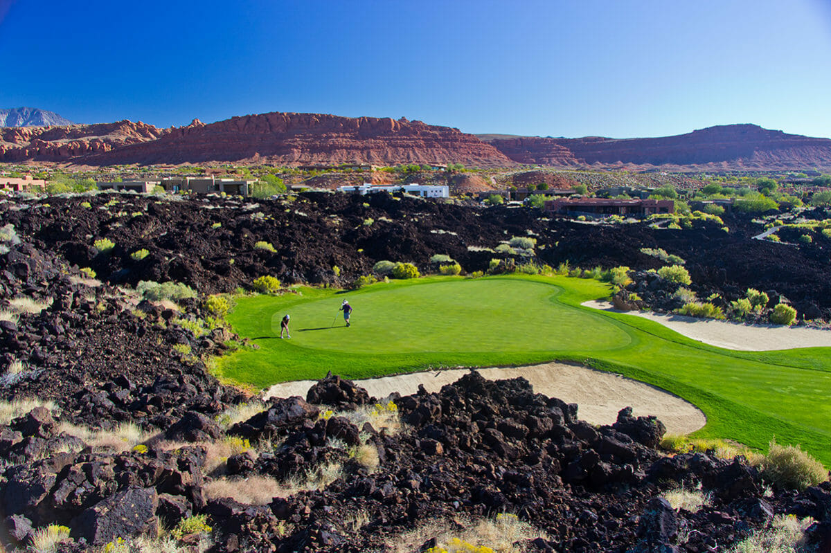 Couple on green surrounded by black lava rocks.