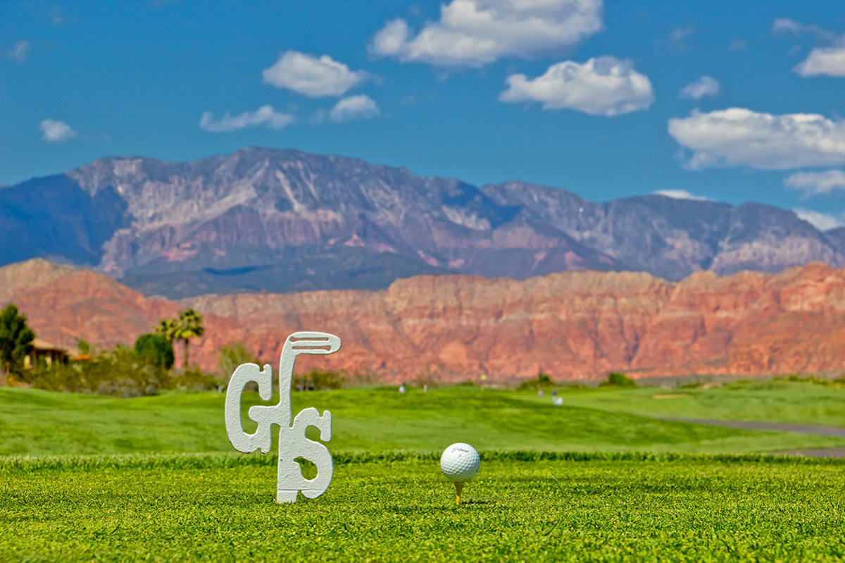 View of golf tee with large mountains in the background