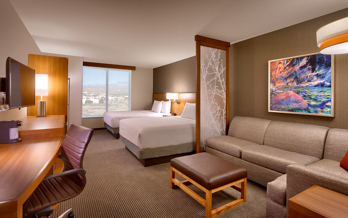 Modern hotel suite with two queen beds and a sofa