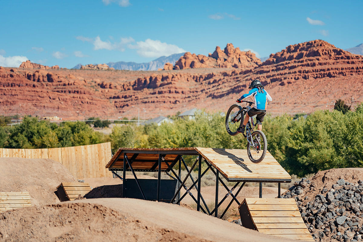 Boy on mountain bike jumping from wooden ramp.