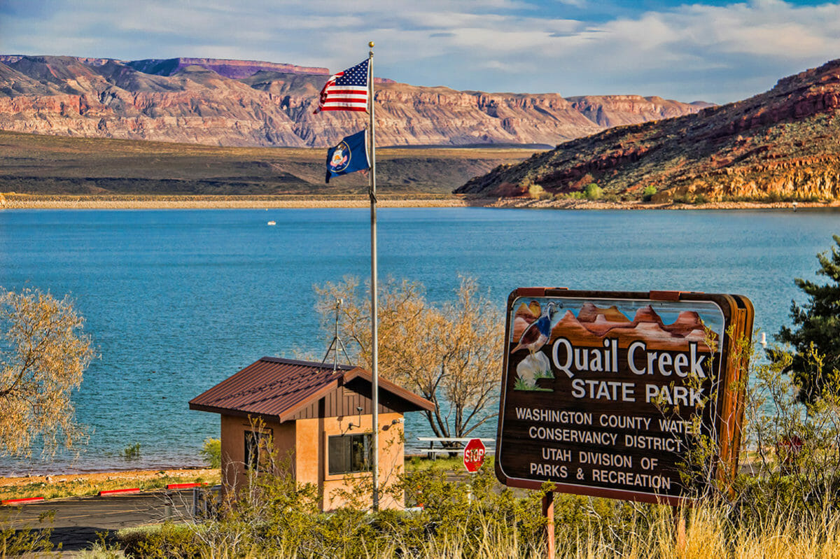 Entrance sign reading Quail Creek State Park in front of blue lake.