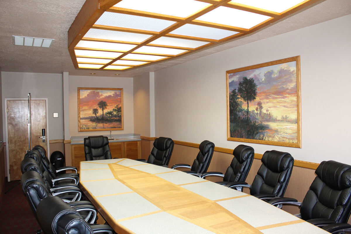 Hotel board room with black leather chairs around long wooden table