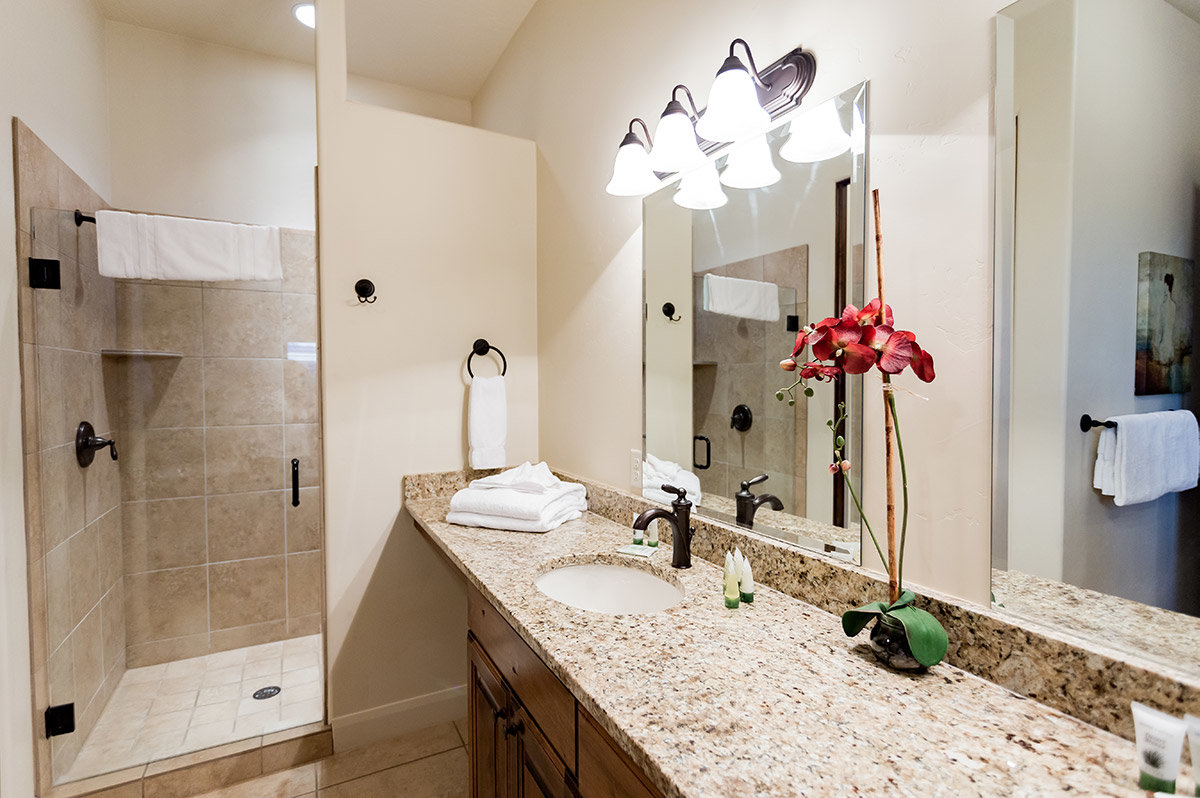 Hotel bathroom with granite countertop and shower with glass door