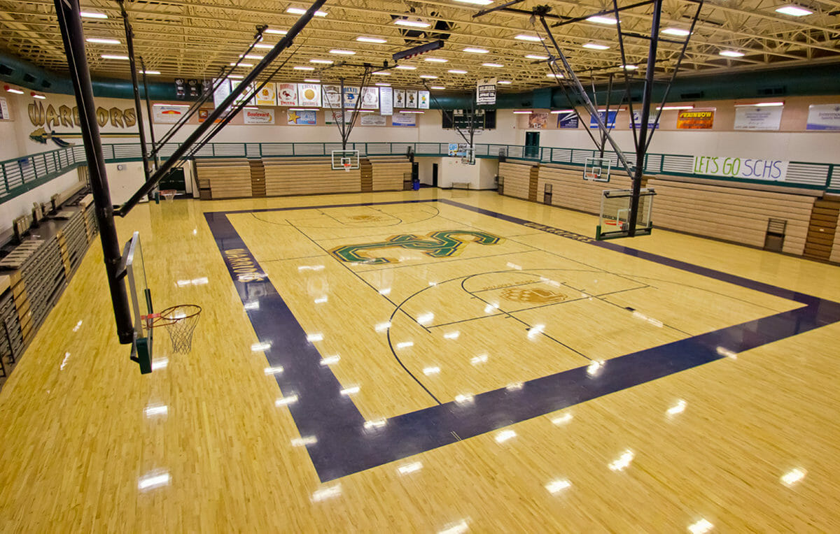 Wide-angle view of indoor basketball court with wood floor