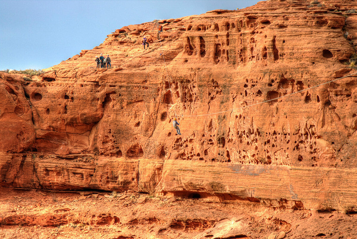 Wide view of man on zipline over canyon.